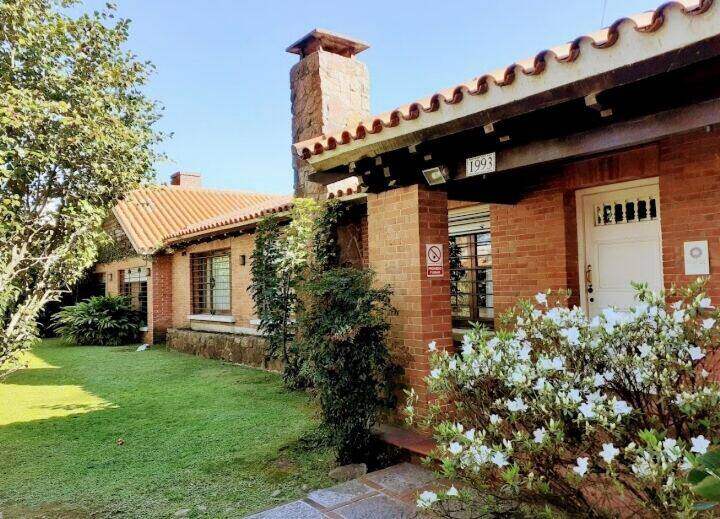 Frente de la casa con la chimenea y flores blancas
